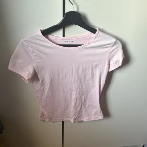 Ljusrosa kortärmad topp från Shein - Säljer en söt ljusrosa topp från Shein. Den är kortärmad och har en enkel design som passar perfekt till vardags. Toppen är gjord i ett mjukt material och har en rund halsringning.