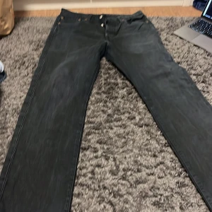 Svarta jeans från Levi's - Snygga svarta Levi's jeans med knappgylf och klassisk femficksdesign. Perfekta för en stilren look. Passar till många olika tillfällen och outfits.