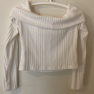 Vit ribbad offshoulder topp från NLY - Snygg vit ribbad offshoulder topp från NLY. Perfekt för en stilren look med långa ärmar och en tight passform. Passar utmärkt till både jeans och kjol för en trendig outfit.