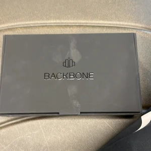 Backbone One spelkontroll - Säljer en Backbone One spelkontroll i grått och svart. Perfekt för att förvandla din smartphone till en spelkonsol. Inkluderar en USB-C anslutning och ergonomisk design för bekvämt spelande. Kommer i originalförpackning med QR-kod för appnedladdning.