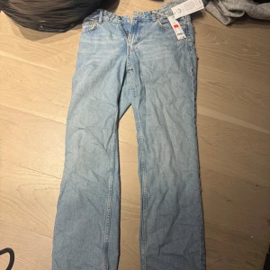 Jeans - Säljer ett par blå low straight jeans med låg midja. De har en klassisk femficksdesign och en dragkedja med knapp framtill. Perfekta för en avslappnad stil.