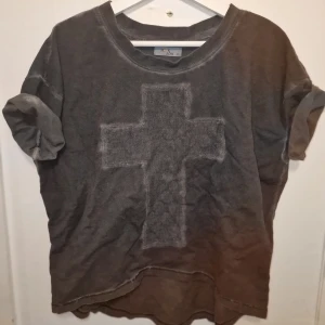 Grå t-shirt med kors från Monrow - Säljer en grå t-shirt från märket Monrow med ett stort kors på framsidan. T-shirten har en avslappnad oversize passform. Perfekt för en casual look. Garderobsrensning så kika gärna på övriga auktioner.