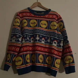 Färgglad jultröja från Lidl - Säljer en färgglad jultröja från Lidl med deras logotyp i ett mönster av rött, blått och gult. Den kommer inte till stor användning hemma hos mig men tänkte sälja för jag vet att den är svår och få tag på