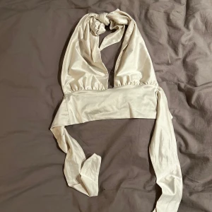 Beige halterneck topp - Snygg beige halterneck topp med knytband i nacken. Perfekt för en somrig look eller en utekväll. Toppen har en stilren design och är tillverkad i ett mjukt material. Den är i storlek S🥰