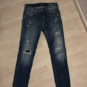 Blå jeans Replay jeans med slitningar - Snygga blå jeans från Replay i modellen Anbass. De har en slim fit passform och har feta slitningar. Strl W27 L30