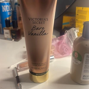 Victoria's Secret Bare Vanilla Fragrance Lotion - En lyxig doftlotion från Victoria's Secret med doften Bare Vanilla. Förpackningen är elegant i guld och brons med en kapacitet på 236 ml. Perfekt för att återfukta huden och ge en långvarig, söt vaniljdoft.