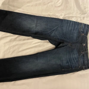 Mörkblå jeans från Jack & Jones - Snygga mörkblå jeans från Jack & Jones med klassisk femficksdesign och kontrastsömmar. Perfekta för en avslappnad stil. Märkeslapp i läderimitation baktill.