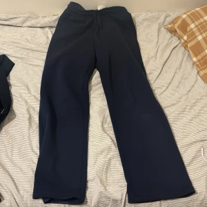 Mörkblå mjukisbyxor från Gina tricot  - Säljer ett par mörkblå mjukisbyxor från Gina troicot. Byxorna har en bekväm passform med resår och snörning i midjan. Perfekta för en avslappnad stil.