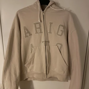 Axel Arigato Zip Up Hoodie  -  Sällsynt Beige Axel Arigato hoodie. Två fickor på bröstet under texten ARIGATO. Sälj pga ingen användning. Passform är kort mage och långa armar. Priset är ej hugget i sten💸(nypris ca 2 600 kr)kan mötas upp i Stockholm 🏙️🏢hör gärna av er vid frågor? 100%bomull 