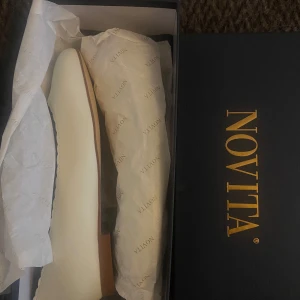 Vita ballerinaskor från Novita - Hej, jag säljer dessa eleganta krämvita ballerinaskor från Novita med rundad tå och tidlös design. Perfekta för en stilren look. Skorna kommer i originalförpackning och är helt oanvända. 