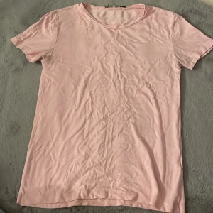 Ljusrosa t-shirt från 157 - Säljer en ljusrosa t-shirt från 157 i mjukt material. Den har en klassisk rund hals och korta ärmar, perfekt för en avslappnad stil.