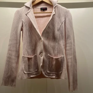 Babyrosa stickad kavaj - Elegant babyrosa stickad kavaj med två knappar framtill och praktiska fickor. Den har en klassisk krage och långa ärmar, perfekt för en stilren look.  Är S men kanske mer än xs beroende på hur man vill att den sitter😇