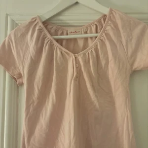Ljusrosa babydoll topp från Jackpot - Säljer en söt ljusrosa topp från Jackpot med korta ärmar och knappar framtill. Perfekt för en avslappnad stil. Storlek 1, skulle säga xs💞