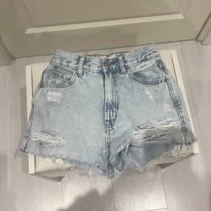 Ljusa jeansshorts med slitningar - Snygga ljusa jeansshorts med slitna detaljer och fransig kant. Perfekta för en avslappnad stil. Klassisk femficksdesign och knappgylf.