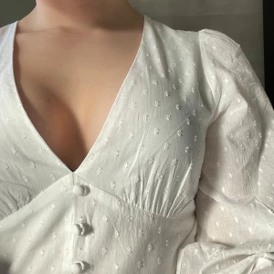 Studentklänning - Vit kort studentklänning från Nelly med v-ringning och långa ärmar🩷Endast använd en gång. Inga defekter. Perfekt för examen eller midsommar!💐💐