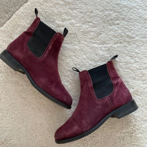Vinröda Chelsea boots i mocka - Snygga vinröda Chelsea boots i mocka med elastiska sidopaneler och låg klack. Perfekta för en stilren look.