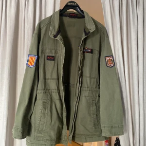 Grön jacka med patches - Säljer en DIY Field jacket som är modifierad med patches och coola mönster, den är i perfekt skick. Jag säljer den eftersom den var för stor på mig. Perfekt för höst och vår. Kan mötas upp för köp inom Stockholm/Norrtälje 