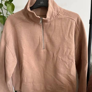 Beige tröja med dragkedja från Klo Essentials - Säljer en supermysig beige tröja. Den har en halv dragkedja framtill och är gjord i ett mjukt material som känns skönt mot huden. Perfekt för höst och vinter! Tröjan har långa ärmar och ribbade muddar vid ärmslut och nederkant. 