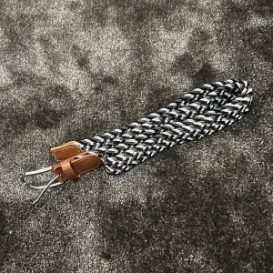 Flätat bälte med läderdetaljer - Säljer ett snyggt flätat bälte i svart och vitt med bruna läderdetaljer. Bältet har en silverfärgad spänne och är perfekt för att ge en stilren touch till din outfit. Passar både till vardags och fest!