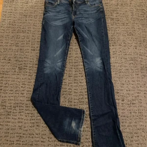 Blå jeans - Säljer ett par snygga blå jeans med en klassisk look. De har en lätt slitning på låren och knäna för en cool, avslappnad stil. Perfekta för vardagsbruk! raka