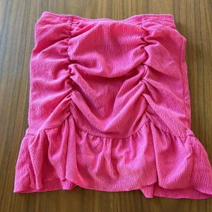 Rosa kjol från Gina Tricot - Säljer en superfin rosa kjol från Gina Tricot! Den har en snygg rynkad design och volanger som ger en extra touch. Perfekt för sommarens alla fester eller bara en dag på stan. Kjolen är i ett mjukt och bekvämt material.