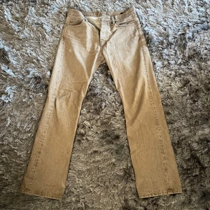 Beige jeans från Hope - Säljer ett par snygga beige jeans från Hope i modellen Rush Jeans. De har en klassisk straight fit och är perfekta för både vardag och fest. Byxorna är i bra skick och har en stilren design med knappar och dragkedja. Passar perfekt till höst- och vårgarderoben!