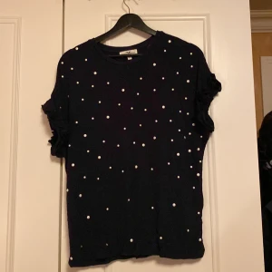 Mörkblå blus med vita prickar  från Hampton Republic - Säljer en snygg mörkblå blus från Hampton Republic med vita prickar över hela. Perfekt för både vardag och fest! Tröjan har korta ärmar och är i mycket bra skick. Passar perfekt till jeans eller kjol för en stilren look. Volang längst ut på armarna 🤩