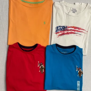 Klädpaket med två Ralph lauren + två us polo assn - Säljer klädpaket med en vit långärmad tröja från ralp lauren, en orange Ralph lauren T-shirt och två nya us polo assn tröjor. Alla är i strl 18-20/170. Passar xs-s. 150kr för allt!