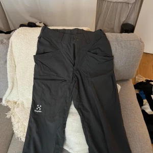 Svarta byxor från Haglöfs - Säljer ett par svarta byxor från Haglöfs i storlek 36. De är perfekta för utomhusaktiviteter med flera praktiska fickor och en bekväm passform. Byxorna har en elastisk midja och är i mycket bra skick.