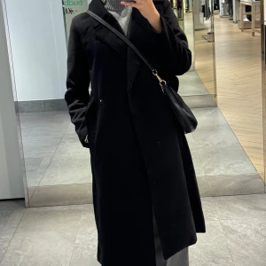 Svart kappa med knytskärp  - Säljer en elegant svart kappa i mycket bra skick. Knytskärp och två knappar. Jag är 173cm för referens. 