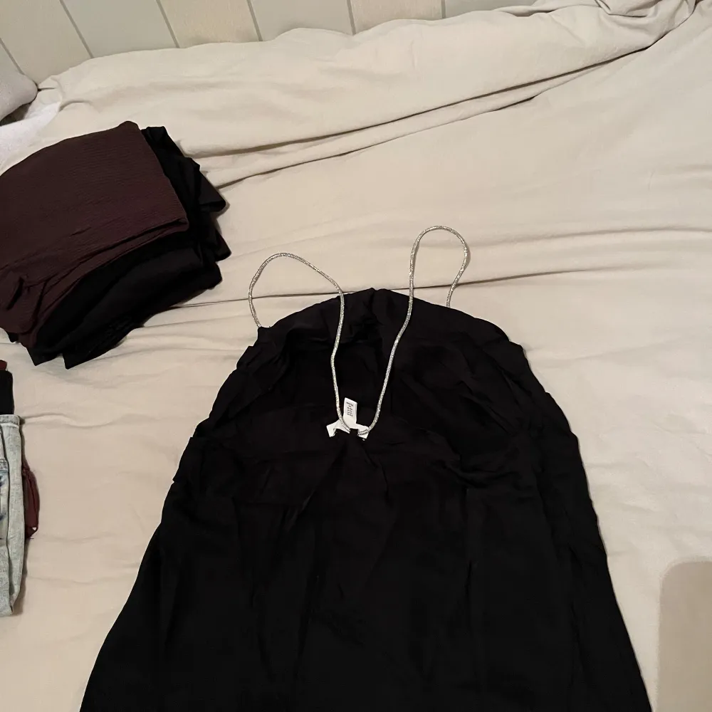 Säljer en elegant svart linne från H&M med tunna axelband. Perfekt för festliga tillfällen! Linnet har en enkel och stilren design som passar till många olika accessoarer. Den är i bra skick och redo för nya äventyr.. Yläosat.