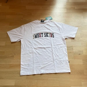 Vit t-shirt från Sweet SKTBS - Vit t-shirt från Sweet SKTBS i storlek XL. Helt ny med etikett kvar. Riktigt snygg. Säljer för att den inte passar