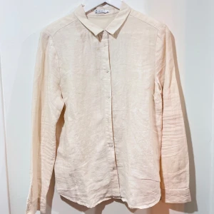 Beige linneskjorta - Säljer en stilren beige skjorta i linne. Perfekt för både vardag och fest! Skjortan har långa ärmar och knappar framtill. 