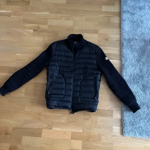 Moncler cardigan - Säljer en snygg svart jacka från Moncler. Jackan har en quiltad design med dragkedja och långa ärmar. Perfekt för höst och vinter, håller dig varm och stilren. Den är i mycket bra skick och knappast använd.