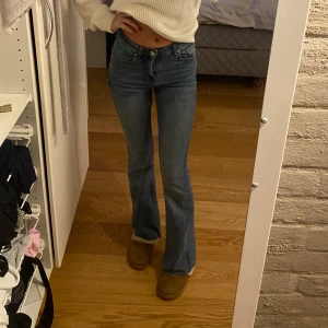 Blå bootcut jeans - Säljer ett par snygga blå bootcut jeans i bra skick. De är lågmidjade och har en klassisk femficksdesign med dragkedja och knapp. Perfekta för både vardag och fest! Passar bra till en stickad tröja eller en snygg topp.