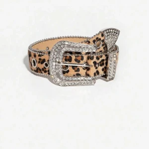 Leopardmönstrat bälte med strass - Snyggt leopardmönstrat bälte med glittrande strassdetaljer på spännet och änden. Perfekt för att ge din outfit en extra touch av glamour. Bältet har även silverfärgade nitar som ger en cool kontrast till det djuriska mönstret. Passar perfekt till både fest och vardag!