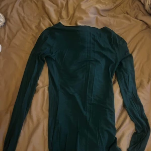 Mörkgrön långärmad tröja - Säljer en stilren mörkgrön tröja från intimissimi med långa ärmar. Inga slitningar. Perfekt för höst och vinter, den är både bekväm och snygg. Passar bra till både vardag och fest. Tröjan har en enkel design som gör den lätt att matcha med andra plagg.