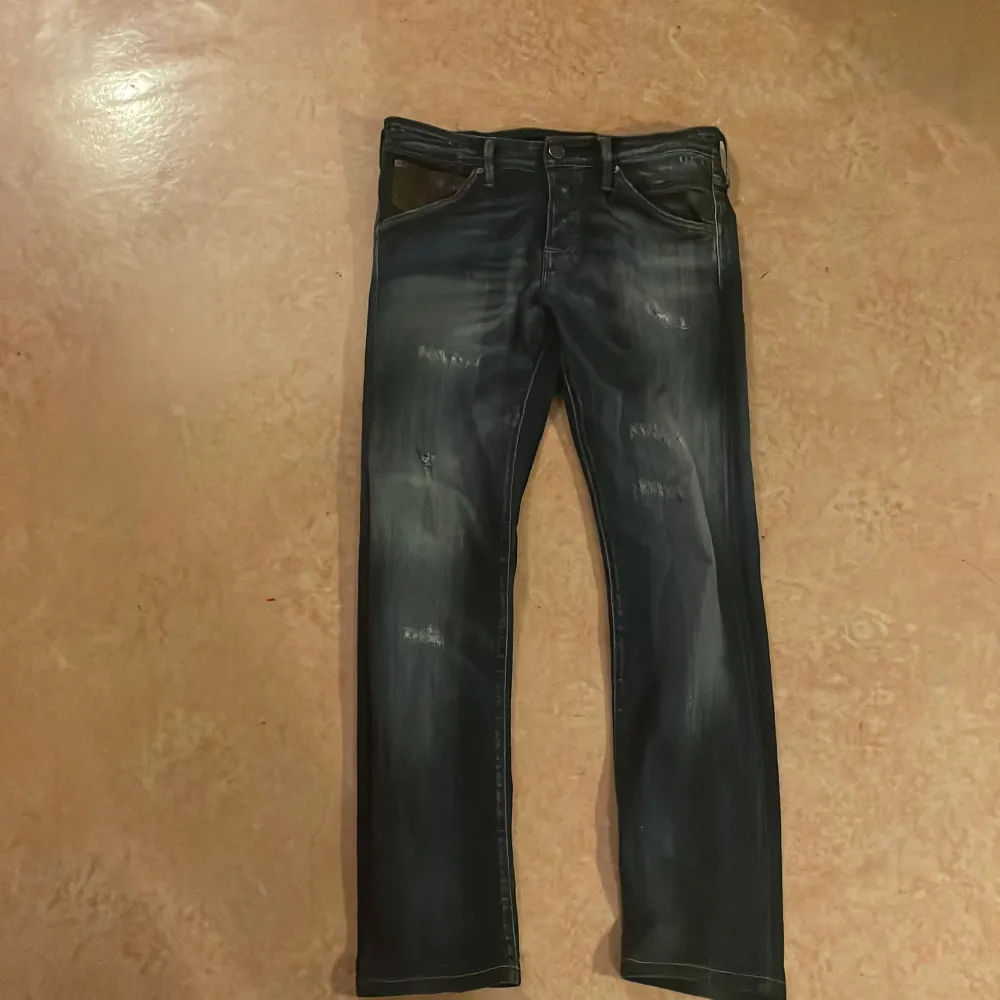 Säljer ett par mörkblå jeans i bra skick med coola slitningar för en avslappnad grisch look. Slim fit killar . Jeans & Byxor.