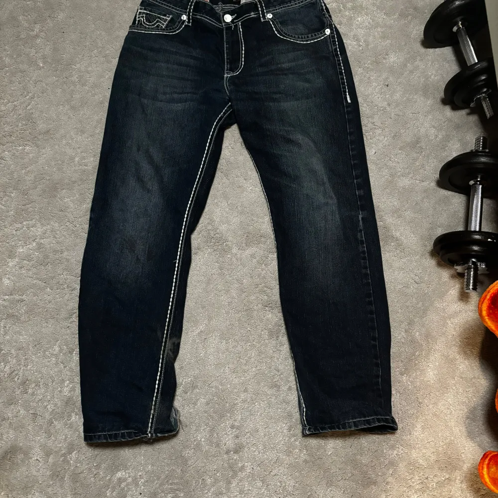 Säljer ett par snygga mörkblå jeans från True Religion. De har en vit kontrast söm och passar bra med nästan alla tröjor. Är i storlek 170cm men passar allt från 160 till 180 . Jeans & Byxor.