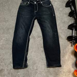 Säljer ett par snygga mörkblå jeans från True Religion. De har en vit kontrast söm och passar bra med nästan alla tröjor. Är i storlek 170cm men passar allt från 160 till 180 