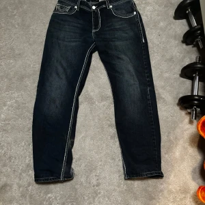 Mörkblå jeans från True Religion - Säljer ett par snygga mörkblå jeans från True Religion. De har en vit kontrast söm och passar bra med nästan alla tröjor. Är i storlek 170cm men passar allt från 160 till 180 