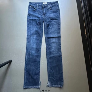 Blå jeans från Acne - Säljer ett par snygga blå jeans från Acne i bra skick. De har en klassisk femficksdesign och en normal passform. Perfekta för både vardag och fest! De har ett klippt litet slit längst ned och midjemåttet tvärsöver är ungefär 40 cm. De har även ett litet hål mellan benen.