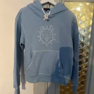 Ljusblå hoodie från SEAMS  - Säljer en ljusblå hoodie från Seams i storlek S. känguruficka och  huva med vita snören. 