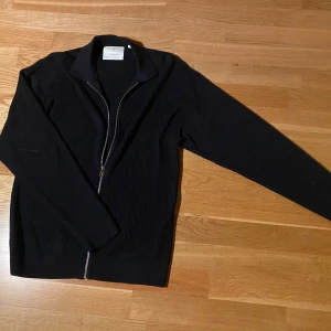 Mörkblå ribbad tröja från Jack & Jones - Säljer en stilren mörkblå ribbad tröja från Jack & Jones. Den har en dragkedja framtill och långa ärmar, perfekt för både vardag och lite finare tillfällen. Tröjan är i bra skick och passar till det mesta. Perfekt för höst och vår. Passar som M. Priset går såklart att diskutera! 