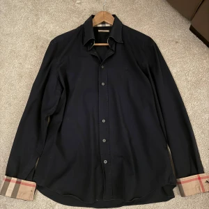 Burberry skjorta navy - Säljer min feta burberry skjorta i färgen navy. Använd fåtal gånger, storlek XL men sitter som L. Skick 8/10 pga 2 knappar som är halvt trasiga 