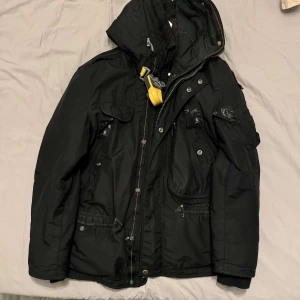 Svart vinterjacka från Parajumpers - Säljer en svart Parajumpers vinterjacka i mycket bra skick. Den har en quiltad insida och en avtagbar luva. Jackan är långärmad med flera praktiska fickor och en dragkedja framtill. Perfekt för kalla vinterdagar. Ny pris 11 599kr.🖤