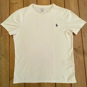 Vit Ralph Lauren T-Shirt  - Säljer nu denna sjukt snygga Ralph Lauren T-Shirt. Storlek M. Skick 9/10 knappt använd, inga defekter. Nypris ca 699kr. Hör av dig om du undrar något eller vill ha fler bilder!  Kom med bud om priset inte passar!