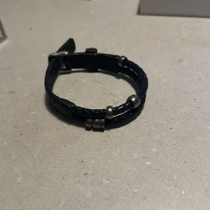 Svart flätat armband - Snyggt svart flätat armband med silverdetaljer. Perfekt för både vardag och fest. Armbandet har en stilren design med små silverpärlor som ger det en extra touch. Passar de flesta handleder tack vare sin justerbara storlek.