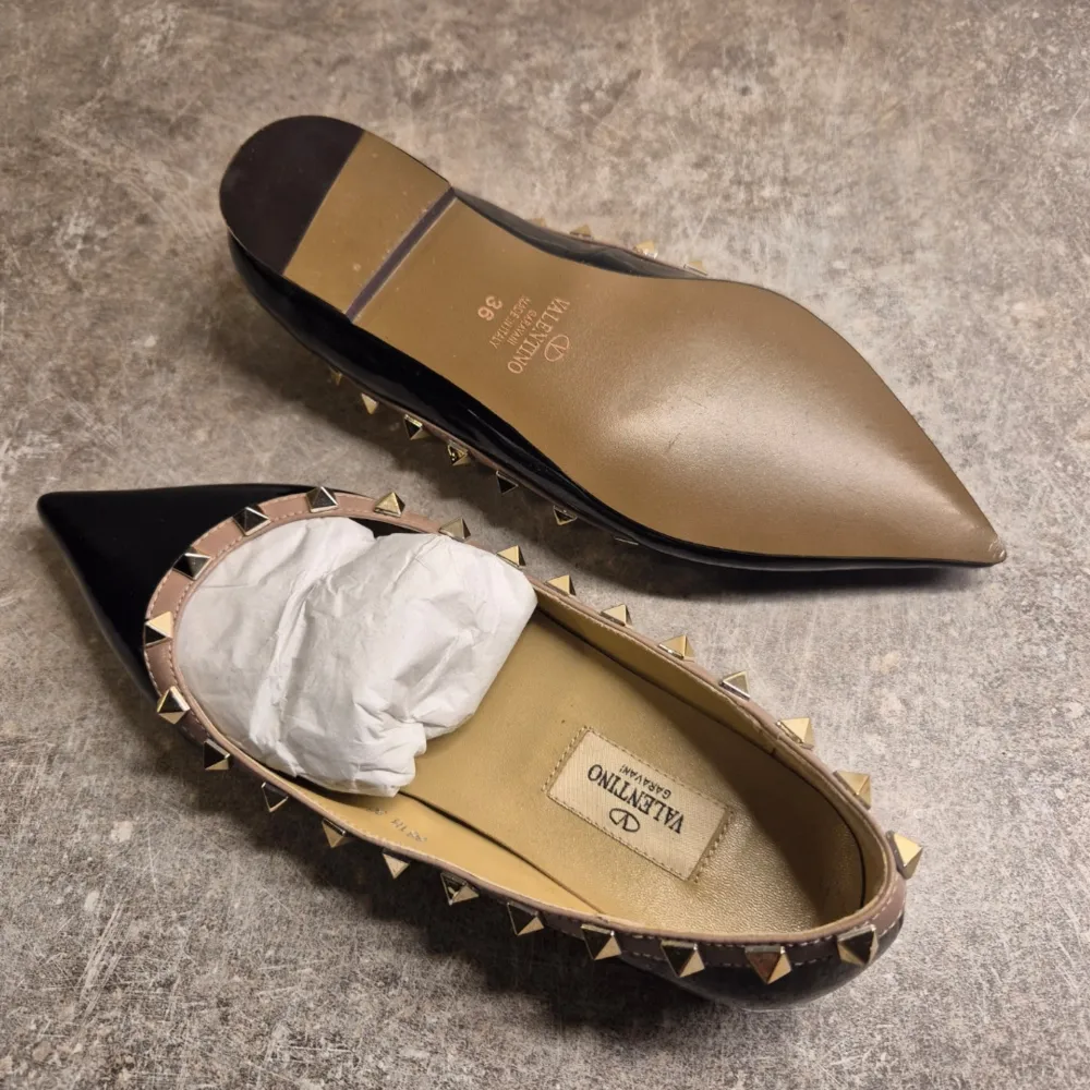 Snygga svarta ballerinaskor från Valentino med spetsig tå och ikoniska nitar runt kanten. Skorna har en elegant design som passar perfekt för en stilren look.. Kengät.