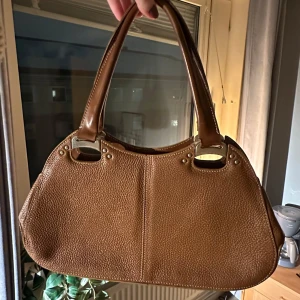 Brun handväska vintage  - Snygg brun axelremsväska i skinn med stilrena detaljer och dragkedjor. Väskan är köpt second hand, märke: Scala. Rymlig väska där allt man behöver får plats🤗hör av dig vid frågor eller fler bilder.